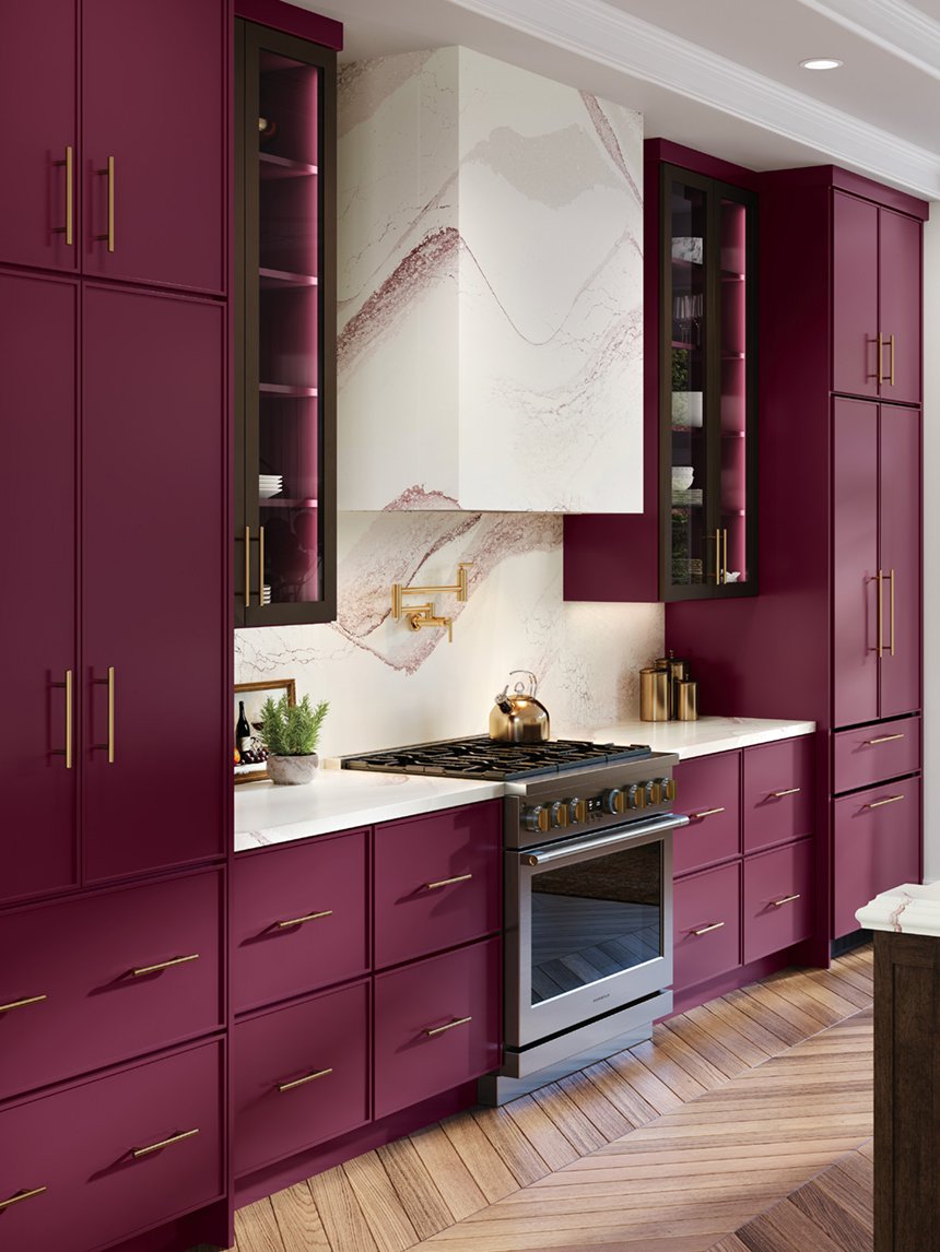 Deep red custom cabinetry with brass hardware and a marble hood surround