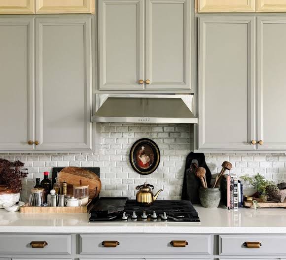 Painted kitchen cabinets with a stainless range hood and tile backsplash