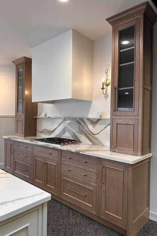 Wood cabinetry with a paneled range hood and brass sconce lighting